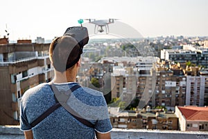 Young technician man flying UAV drone with remote control in city