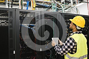 Young technician man working with tablet inside big data center room - Soft focus on face