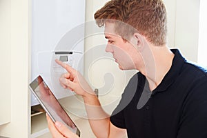 Young technician servicing a boiler, using tablet computer