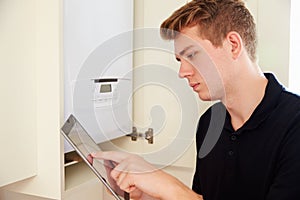 Young technician servicing a boiler, using tablet computer photo