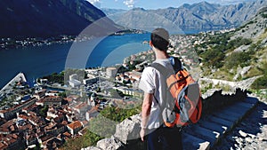 Young teen admires the view during the ascent to the fortress in Kotor in Montenegro. Male brunette in white t-shirt