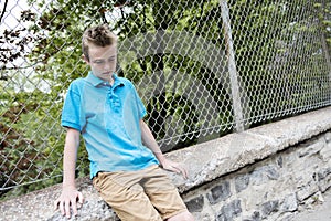 Young teen boy looking out of a fence