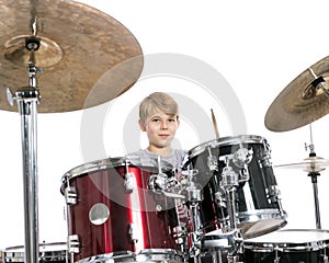 young teen boy plays the drums in studio against white background