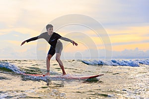 Young teen boy surfer riding waves on soft board in Rayong beach, Thailand. Rookie teenager surfboard student playing on water in