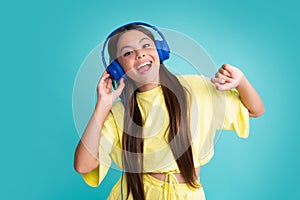 Young teen child listening music with headphones. Girl listening songs via wireless headphones. Wireless headset device