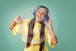 Young teen child listening music with headphones. Girl listening songs via wireless headphones. Wireless headset device