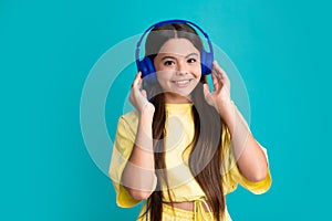 Young teen child listening music with headphones. Girl listening songs via wireless headphones. Wireless headset device