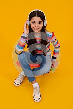 Young teen child listening music with headphones. Girl listening songs via wireless headphones. Wireless headset device