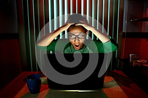 Young Teen with eyeglasses acting surprised in front of a laptop computer