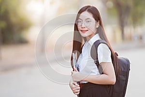 Young teen female Asian university student with bagpack holding laptop in the university campus. Female university student go to u photo