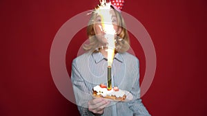 Young teen girl in birthday cap holding cake with candle