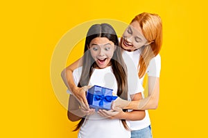 Young teen girl giving gift box to her mother on color background. Happy family. Mother and daughter with present gift.