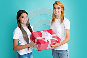 Young teen girl giving gift box to her mother on color background. Happy family. Mother and daughter with present gift.