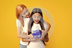 Young teen girl giving gift box to her mother on color background. Happy family. Mother and daughter with present gift.
