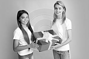 Young teen girl giving gift box to her mother on color background. Happy family. Mother and daughter with present gift.