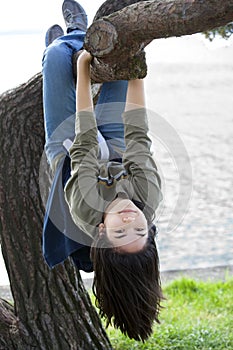 Young teen girl hanging on tree limb