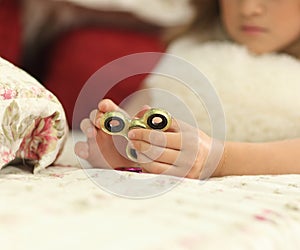 Young teen girl holding popular fidget spinner toy - closeup shot. at home on bed