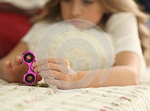 Young teen girl holding popular fidget spinner toy - closeup shot of spinner, home interior