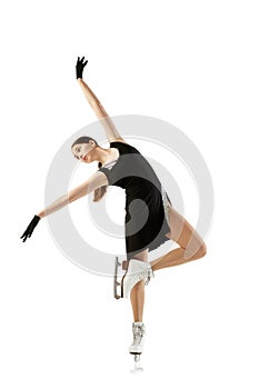 Young teen girl, junior female figure skater in black stage costume skating isolated over white background. Concept of