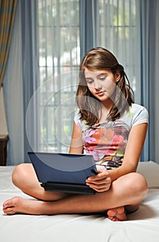 Young teen girl laying on her bed with notebook