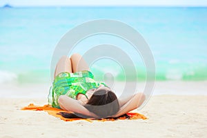 Young teen girl lying on back at tropical beach