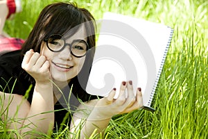 Young teen girl with notebook at green grass