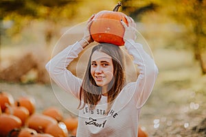 Young teen girl posing with pumpkin on a pumpkin`s field. Copy space