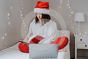 Young teen girl in red santa hat shopping online buying Christmas gifts
