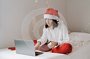 Young teen girl in red santa hat shopping online buying Christmas gifts