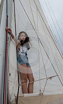 Young teen girl standing on the boom of a saillboat