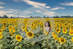 Young teen girl standing in field surrounded by sunflowers