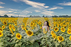 Young teen girl standing in field surrounded by sunflowers