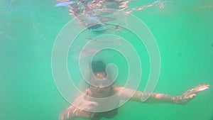 Young teen girl swimming underwater to us