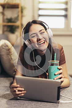 Teen girl using digital tablet computer listening music at home