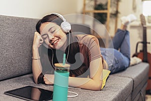 Teen girl using digital tablet computer listening music at home