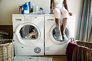 Young teen girl waiting for clothes to be washed from washing machine