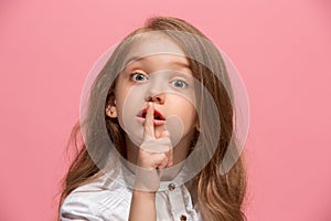 The young teen girl whispering a secret behind her hand over pink background