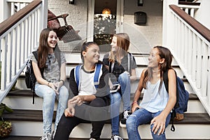 Young teen girls on front steps of house with school bags