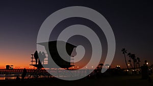 Young teen girls silhouettes, lifeguard watch tower, friends on pacific ocean beach, California USA.