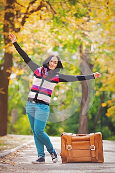 Young teen girt with suitcase in a park