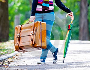 Young teen girt with suitcase and umbrella
