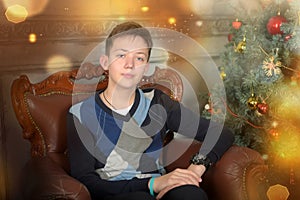 Young teen guy in a chair by the Christmas tree