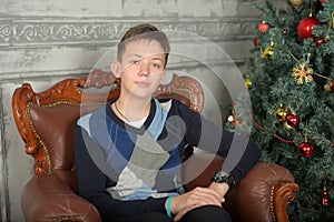 Young teen guy in a chair by the Christmas tree