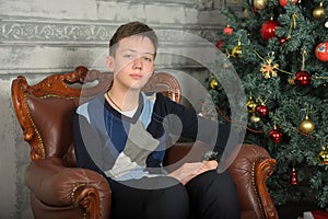 Young teen guy in a chair by the Christmas tree