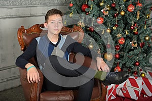 Young teen guy in a chair by the Christmas tree