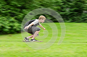 Young teen guy fast rides a skateboard in park