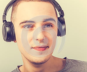 Young teen guy listening the misic on black wireless headphones with fun happy face