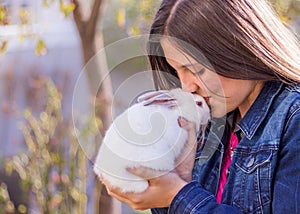 Young teen holding a baby white rabbit kissing it on the forehead