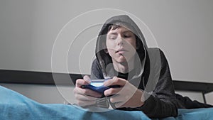 Young teen and joystick man cybersport hooded sweater absorbed In online video game. boy teenager in the hood playing