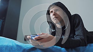 Young teen and joystick man hooded sweater absorbed In online lifestyle video game. boy teenager in the hood playing